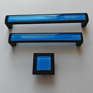 May include: Set of three cabinet hardware pieces: two rectangular pulls and one square knob. Each piece features a black frame with a vibrant blue glass insert. Ideal for updating kitchen or bathroom cabinets.