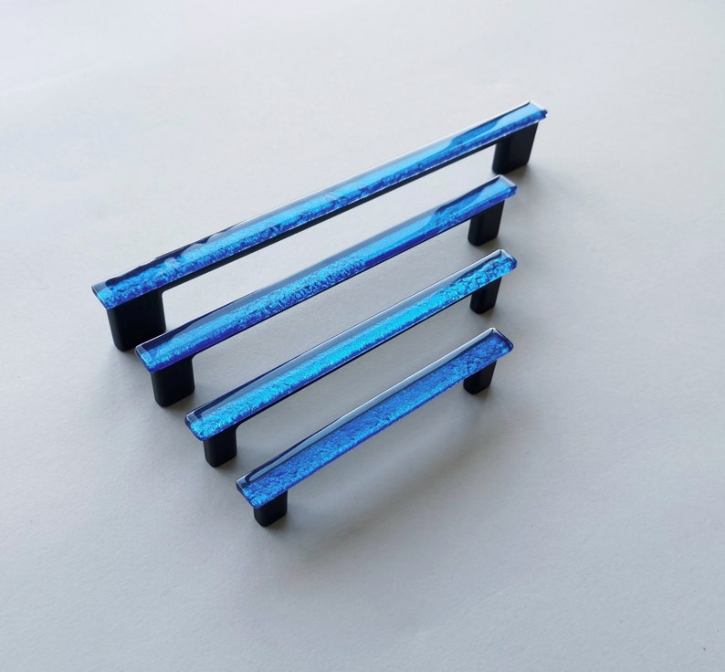 Fired glass cabinet pulls in sparkly bright blue made of fine glass sticks attached over a metal base. Slightly textured glass furniture handles with rounded edges.