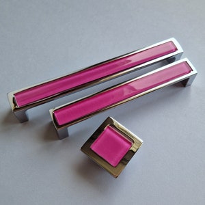 Peut inclure: Trois boutons de porte en verre rose avec une garniture chromée. Les boutons sont de forme rectangulaire et carrée.