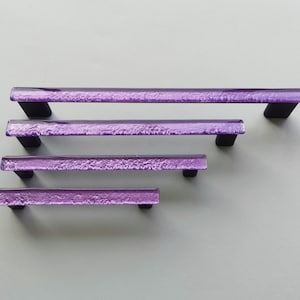 Fired glass cabinet pulls in sparkly purple made of fine glass sticks attached over a metal base. Slightly textured glass furniture handles with rounded edges.