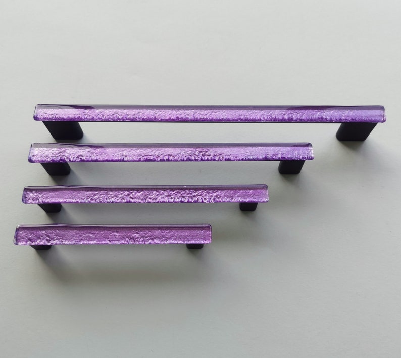 Fired glass cabinet pulls in sparkly purple made of fine glass sticks attached over a metal base. Slightly textured glass furniture handles with rounded edges.