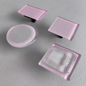Peut inclure: Quatre boutons de porte en verre rose avec une finition argentée. Les boutons sont de formes différentes, notamment rondes, carrées et rectangulaires.