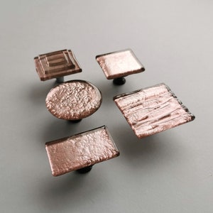 Peut inclure: Cinq boutons de porte en or rose avec différentes formes et textures. Les boutons sont en verre et ont une finition métallique.