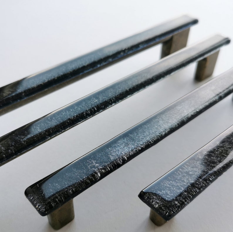 Fired glass cabinet pulls in sparkly bright black made of fine glass sticks attached over a metal base. Slightly textured glass furniture handles with rounded edges.