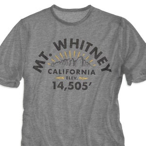 May include: A heather grey t-shirt with a black graphic print of a mountain range with the text "MT. WHITNEY CALIFORNIA ELEV. 14,505'"