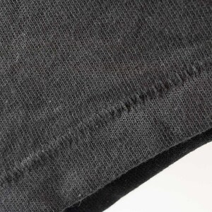 May include: Close-up of the seam of a black t-shirt. The fabric is a soft, knit material.