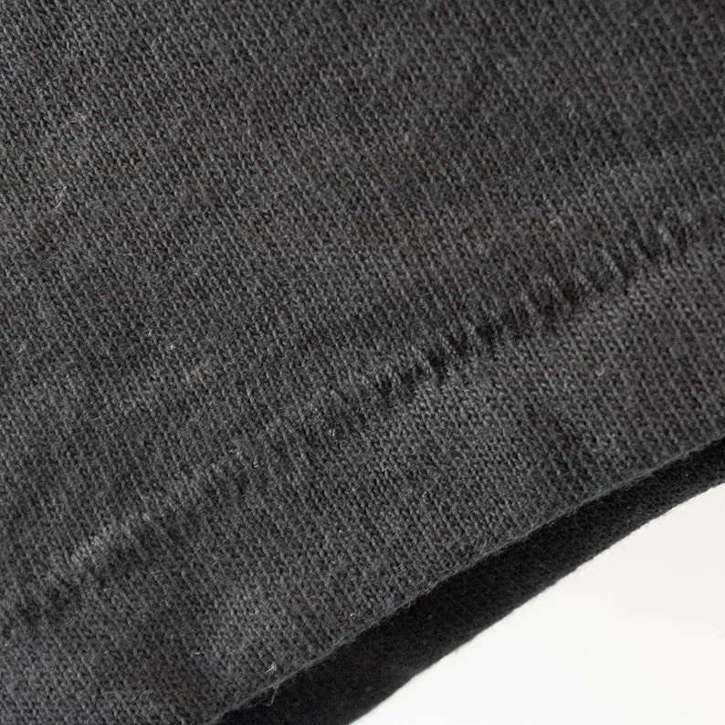 May include: Close-up of the seam of a black t-shirt. The fabric is a soft, knit material.