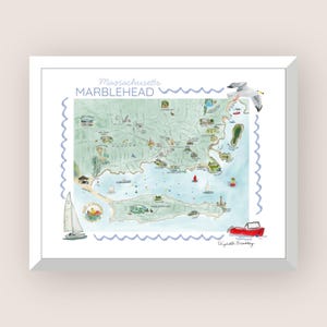 May include: A framed illustrated map of Marblehead, Massachusetts, featuring a light green landmass, blue water, and various coastal landmarks. The print includes a white sailboat, a red motorboat, a seagull, and the text Marblehead.