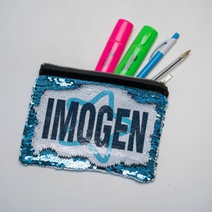 May include: A blue sequin pencil case with the name "IMOGEN" printed in black letters. The case is filled with colourful markers and pens.