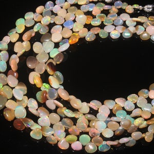 Peut inclure: Un brin de perles de pierres précieuses opales multicolores. Les perles sont de forme ovale et ont une finition lisse et polie. Les perles sont enfilées sur un fil transparent et sont prêtes à être utilisées pour la fabrication de bijoux.