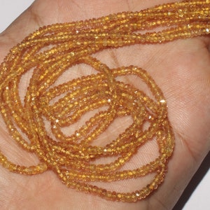 May include: A handful of strands of small, faceted, golden-yellow beads. The beads are strung together, creating a necklace or bracelet material. The beads have a sparkling, reflective quality, suggesting they are made of a gemstone or crystal.