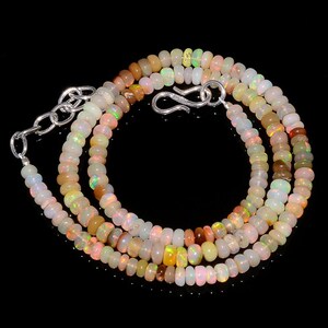Peut inclure: Un collier composé de petites perles d'opale rondes et translucides présentant des éclats iridescents orange, verts et jaunes. Le collier est doté d'un fermoir à crochet en métal argenté et d'une chaînette d'extension réglable.