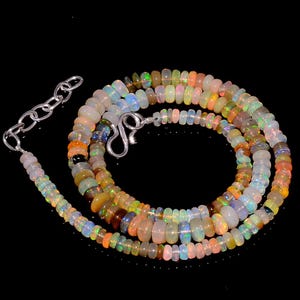 Peut inclure: Un collier composé de petites perles d'opale rondes et translucides affichant un spectre de couleurs irisées, notamment orange, vert, bleu et blanc. Le bijou est doté d'un fermoir en forme de S en métal argenté et d'une chaînette d'extension.