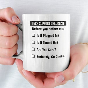 May include: White ceramic mug with a black and white design that says "Tech Support Checklist" and includes a checklist of questions to ask before seeking help. The questions are: "Is it Plugged In?", "Is it Turned On?", "Are You Sure?", and "Seriously, Go Check."