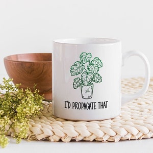 May include: White ceramic mug with a green line drawing of a potted plant and the text "I'd propagate that".