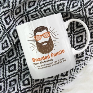 May include: White ceramic coffee mug with a black and brown illustration of a man with a beard and sunglasses. The text on the mug reads "Bearded Funcle (beer-did funk-ul) 1. The most awesome type of uncle. Also the coolest and most fun, ever."