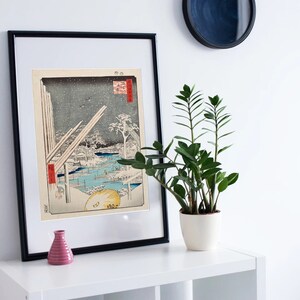 May include: A framed black and white print of a Japanese woodblock print depicting a snowy landscape with a bridge and buildings. The print is titled "Atsu", and the artist's signature is visible in the lower right corner.