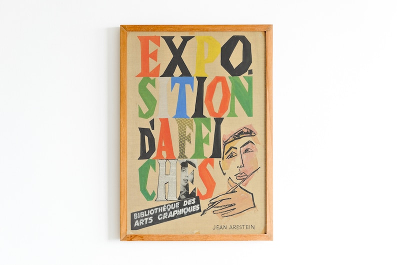 May include: A framed vintage poster with the text "EXPO. SITION D'AFFI. CHES" in colourful, bold letters. The poster features a stylised illustration of a person's face and hand holding a paintbrush. The text "Bibliotheque des Arts Graphiques" and "Jean Aresteain" are also visible.