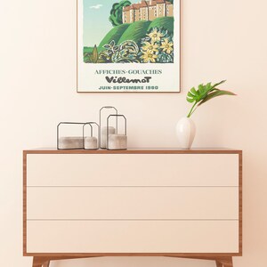 K&ouml;nnte beinhalten: Ein Vintage-Poster, das eine Kunstausstellung mit Plakaten und Gouache-Gem&auml;lden des K&uuml;nstlers Villemot bewirbt. Das Poster zeigt eine farbenfrohe Illustration eines Schlosses mit einem gr&uuml;nen H&uuml;gel und Blumen. Der Text auf dem Poster lautet "Chateau de Boussac (Creuse) Affiches - Gouaches Villemot Juin-Septembre 1980".
