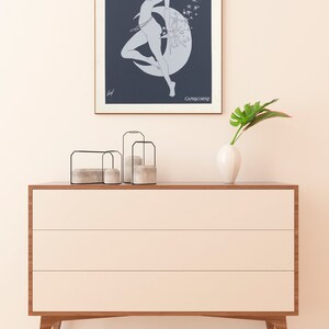 May include: A framed print of a line drawing of a woman standing on a crescent moon with stars in the background. The text "CAPRICORNE" is at the bottom of the print.