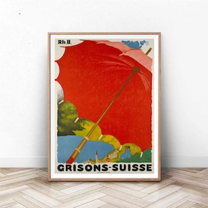 May include: A vintage travel poster advertising the Grisons-Suisse region of Switzerland. The poster features a large red umbrella with a wooden handle, partially covering a colorful landscape with mountains and a town in the distance. The text "Rh.B." and "GRISONS-SUISSE" are printed on the poster.