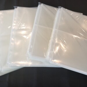 May include: A stack of five clear plastic photo sleeves with a hole punched in the top corner.