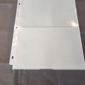 May include: Two clear plastic sleeves with holes punched along the left side. The sleeves are designed to hold and protect documents or photos.