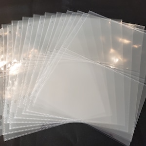 May include: A stack of clear plastic sleeves with holes for a binder. The sleeves have a dotted border and are designed to hold and protect photos, cards, or other paper items.