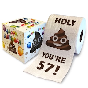 May include: A white toilet paper roll with a brown poop emoji and the text "HOLY YOU'RE 57!" printed on it. The toilet paper is in a cardboard box with a poop emoji and the text "Happy Birthday" printed on it.