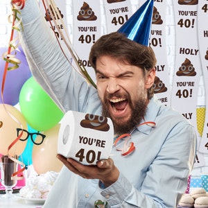 K&ouml;nnte beinhalten: Eine Person h&auml;lt eine Rolle Toilettenpapier mit einem braunen Kack-Emoji und dem Text "You're 40!" darauf. Der Hintergrund ist mit bunten Luftschlangen und Bannern mit dem gleichen Kack-Emoji und Text dekoriert.