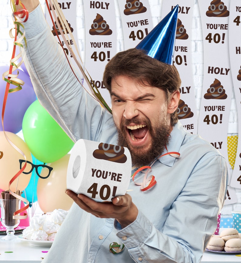 K&ouml;nnte beinhalten: Eine Person h&auml;lt eine Rolle Toilettenpapier mit einem braunen Kack-Emoji und dem Text "You're 40!" darauf. Der Hintergrund ist mit bunten Luftschlangen und Bannern mit dem gleichen Kack-Emoji und Text dekoriert.