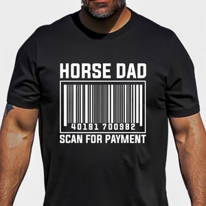 以下が含まれることがあります： 白文字で「HORSE DAD」と書かれた黒いTシャツ。その下に「40181 700982」という番号のバーコードがあり、バーコードの下には「SCAN FOR PAYMENT」という文字が書かれている。