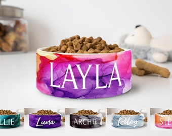 May include: Five personalized pet bowls with abstract watercolor designs. The bowls are teal, purple, black, blue, and orange. The names "Ollie", "Luna", "Archie", "Riley", and "Stella" are printed on the bowls.