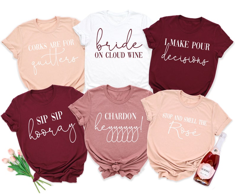 May include: Six different t-shirts with various sayings related to wine. The shirts are in shades of pink, white, and burgundy. The text on the shirts is in white. The shirts are arranged in a circle with a bottle of wine in the center.