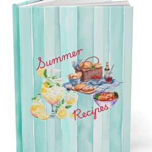 Könnte beinhalten: Ein Notizbuch mit hellblau gestreiftem Einband mit den Worten "Summer Recipes" in roter Schrift. Das Cover-Artwork zeigt eine Aquarell-Picknick-Szene mit Essen, Getränken und einem Korb.