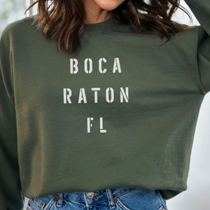 May include: A green sweatshirt with the text "BOCA RATON FL" printed in white.