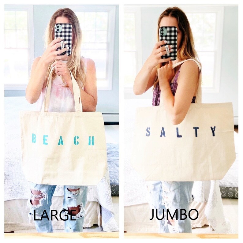 May include: Two canvas tote bags, one with the word "BEACH" in turquoise blue letters and the other with the word "SALTY" in navy blue letters. The bag on the left is labeled "LARGE" and the bag on the right is labeled "JUMBO".