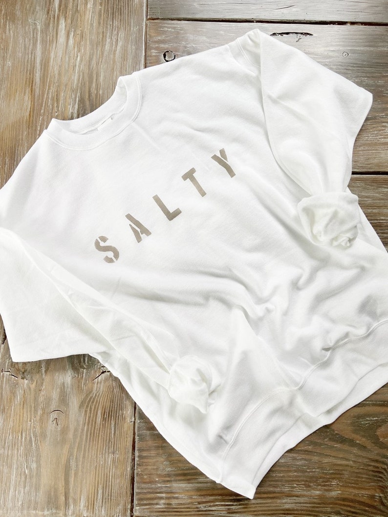 May include: White sweatshirt with the word "SALTY" printed in brown on the front.