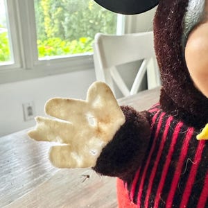May include: Vintage Mickey Mouse plush toy. The plush features a red and black striped shirt, a black head, and a cream-colored felt hand. The toy has a yellow bow tie and a red body.