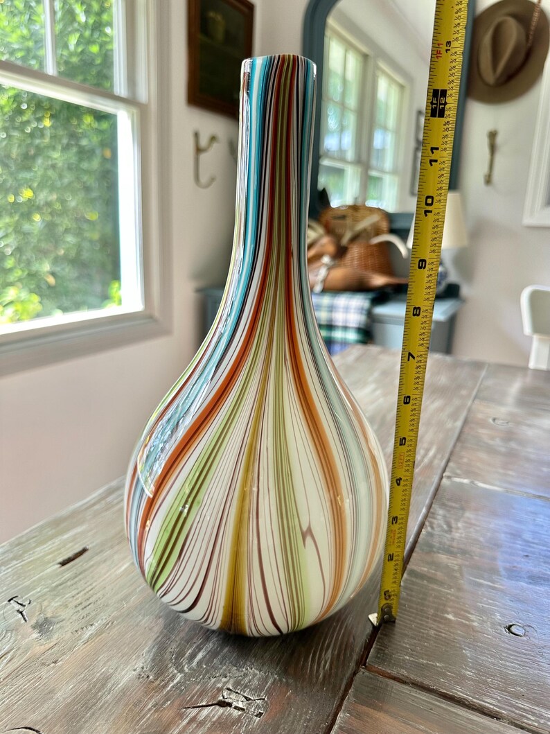 K&ouml;nnte beinhalten: Eine hohe, tropfenf&ouml;rmige Glasvase mit bunten vertikalen Streifen in Blau-, Orange-, Gr&uuml;n- und Braunt&ouml;nen. Die Vase ist etwa 28 cm hoch. Dekorative Heimdekoration.