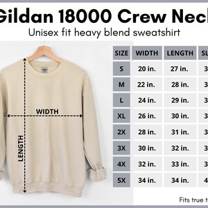 Op de afbeelding: Een beige Gildan 18000 Crew Neck unisex sweatshirt met een maattabel die de afmetingen in inches weergeeft. De tabel omvat maten S tot en met 5X, met breedte-, lengte- en mouwlengtemetingen voor elke maat.