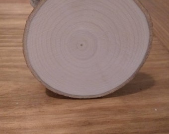 May include: A stack of round wooden slices, each with a natural wood grain pattern and a smooth, light brown surface.