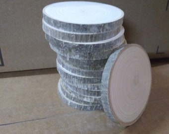 May include: A stack of round wooden slices, some with a natural wood finish and others with a white painted finish. The slices are approximately 10 cm in diameter.