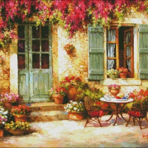 May include: A painting of a quaint cottage with a green door and window, surrounded by lush greenery and flowers. A small table with two chairs sits on the patio, creating a cozy outdoor setting.