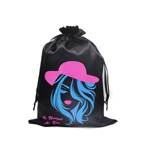 May include: Black satin drawstring bag featuring a graphic of a woman wearing a pink hat and the text "As Unique As You".