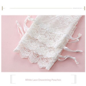 May include: White lace drawstring pouches with delicate floral embroidery and white satin ribbon ties.