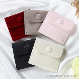 Puede incluir: Cinco bolsitas de terciopelo para joyas en diferentes colores: rojo, gris, rosa, negro y blanco. Cada bolsita tiene un cierre de botón.
