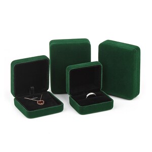 May include: Four green velvet jewelry boxes of different sizes. The largest box is on the right, and the smallest box is on the left. The smallest box has a necklace inside, and the second smallest box has a ring inside.