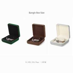 May include: Three square velvet jewelry boxes in green, brown, and gray, each with a bangle inside. The boxes are 9.1 x 9.1 x 4.0 cm and weigh 130 grams.  Bangle Box Size.