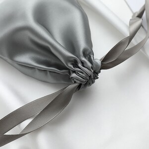 May include: A gray silk drawstring pouch with a gray satin ribbon.